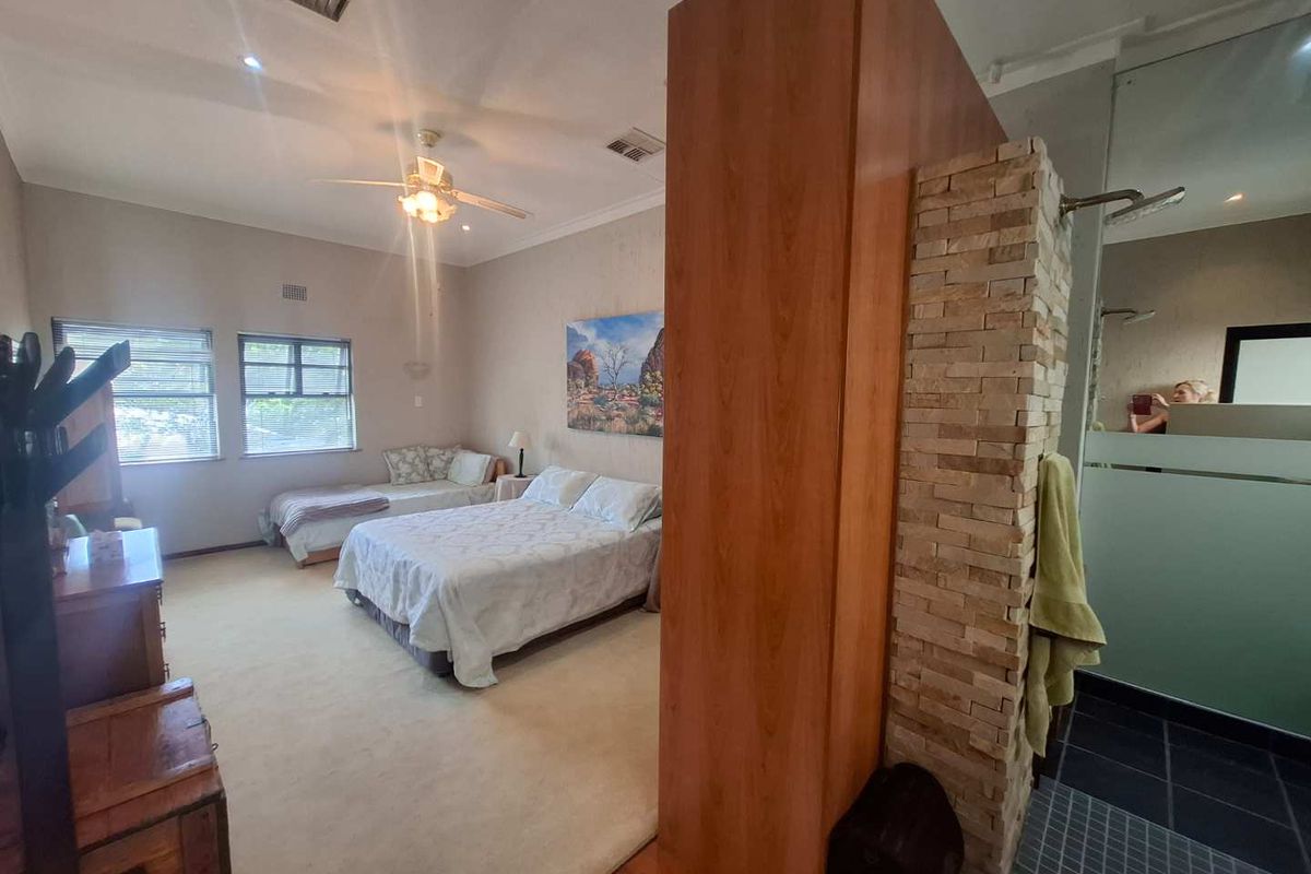 Spacious bedroom featuring an integrated en-suite bathroom area with a stone-clad partition wall and neutral interior finishes.