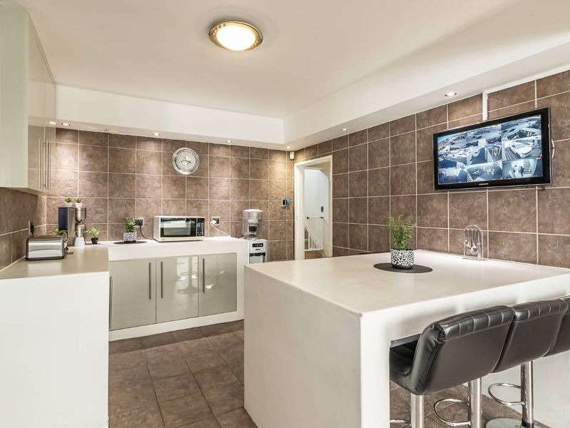 A functional kitchen featuring tiled walls and flooring, built-in cabinetry, and a central breakfast bar island with integrated seating.