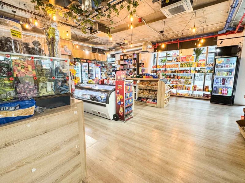 A well-maintained retail space featuring modern laminate flooring, exposed industrial-style ceilings, and integrated commercial refrigeration and shelving units.