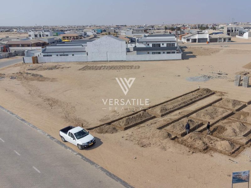 Aerial view of a vacant residential plot showing ongoing foundation excavation work in a developing neighborhood.