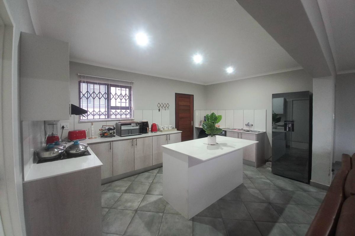 A modern kitchen featuring light-toned cabinetry, a central island with a white countertop, tiled flooring, and integrated appliance spaces.