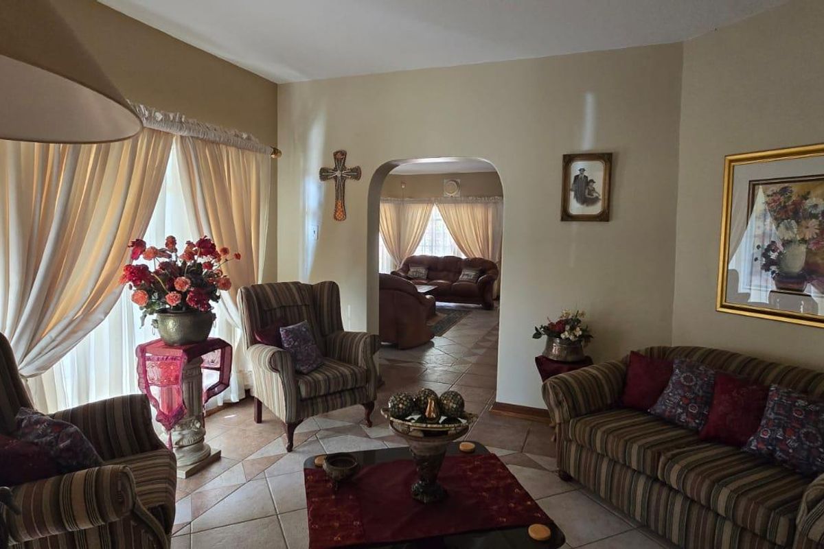 A comfortable living room featuring tiled flooring and an arched doorway leading to an adjacent living space.