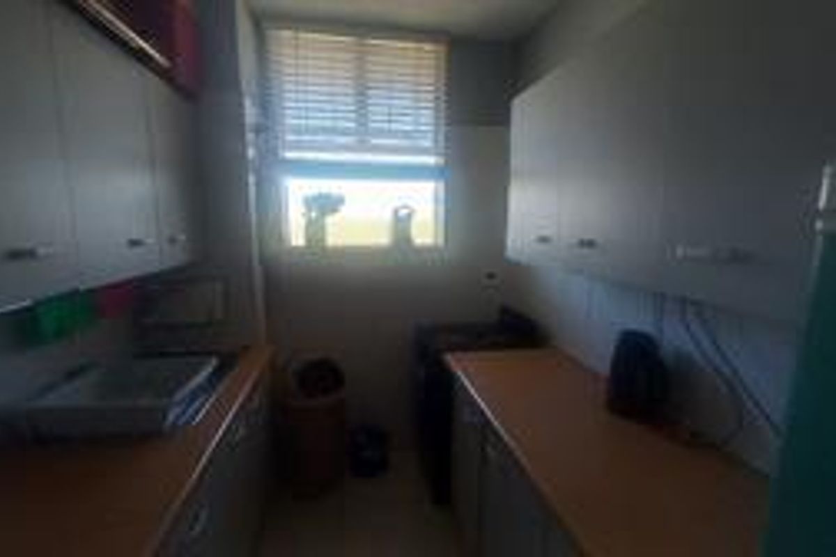 A functional galley-style kitchen featuring built-in cabinetry, laminate countertops, and a window providing natural light.