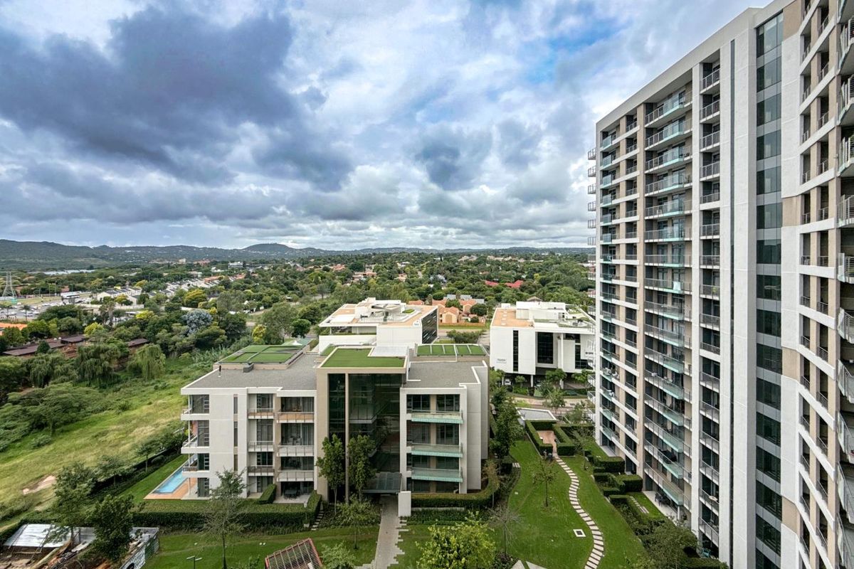 Elevated aerial view of the apartment complex, showcasing modern architecture, landscaped gardens, and surrounding suburban landscape.