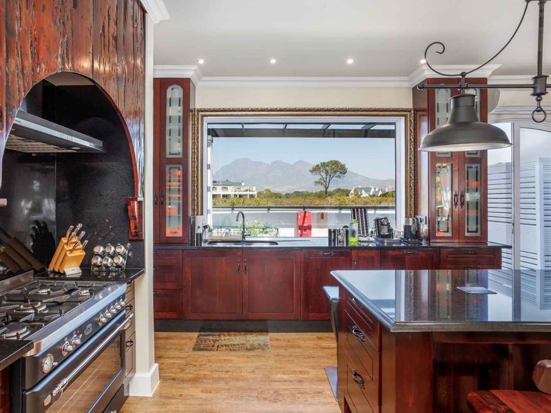 Spacious kitchen featuring dark wood cabinetry, granite countertops, a large central island, and a gas range, with scenic mountain views through the window.