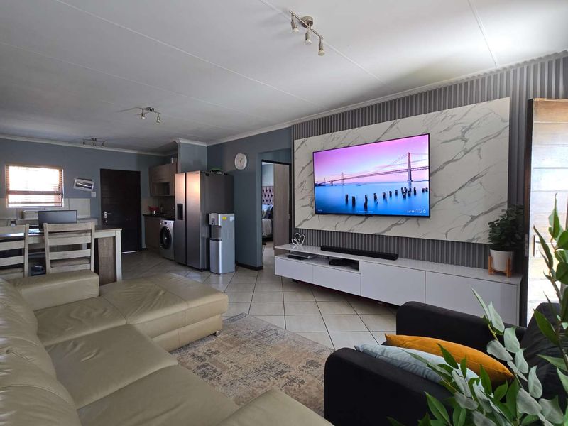 Spacious open-plan living area featuring a modern marble-effect feature wall, tiled flooring, and integrated cabinetry, creating a contemporary and functional living space.