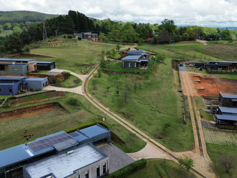 Aerial view of a residential estate featuring modern homes, paved access roads, and landscaped green spaces in a scenic setting.