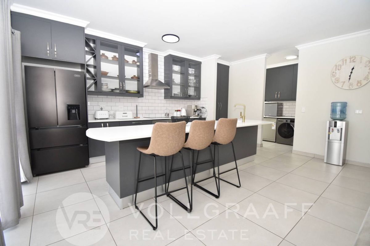 Modern kitchen featuring dark cabinetry, a central island with quartz countertops, subway tile backsplash, and high-quality brass fixtures.