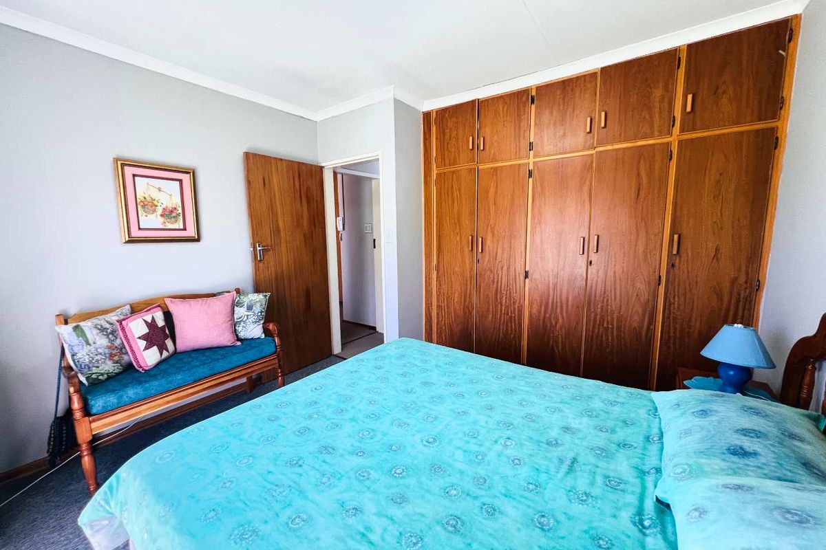 A bedroom featuring extensive floor-to-ceiling built-in wooden cupboards and neutral wall finishes, offering ample storage space.