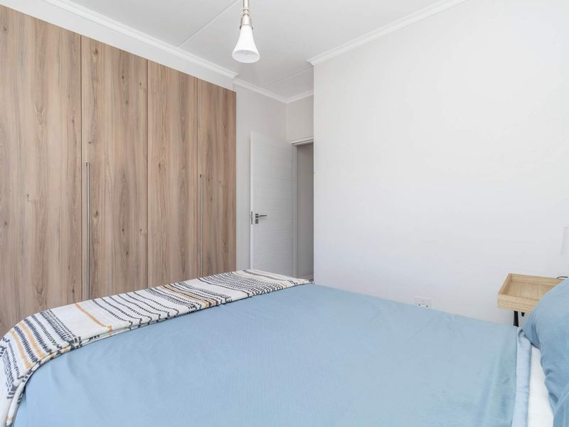 A well-maintained bedroom featuring modern wood-finish built-in cupboards, neutral walls, and classic coving detail.