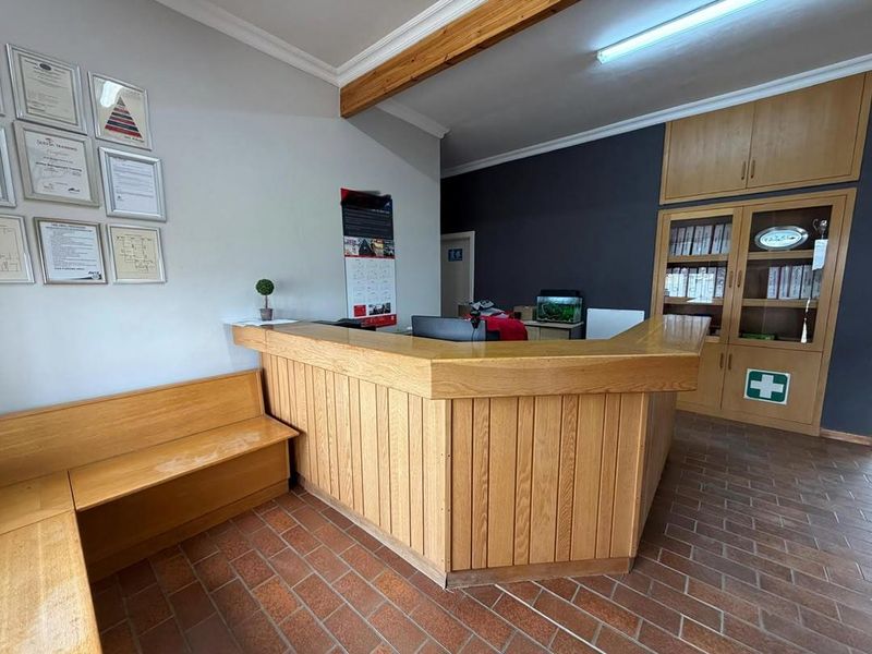 Professional office reception area featuring a custom built-in wooden desk, integrated storage cabinetry, and durable terracotta tile flooring.