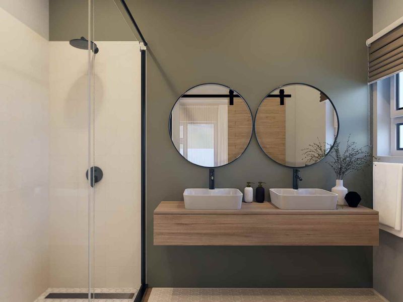 Modern bathroom featuring a floating double vanity with vessel sinks, circular mirrors, and a spacious walk-in shower with a glass screen.