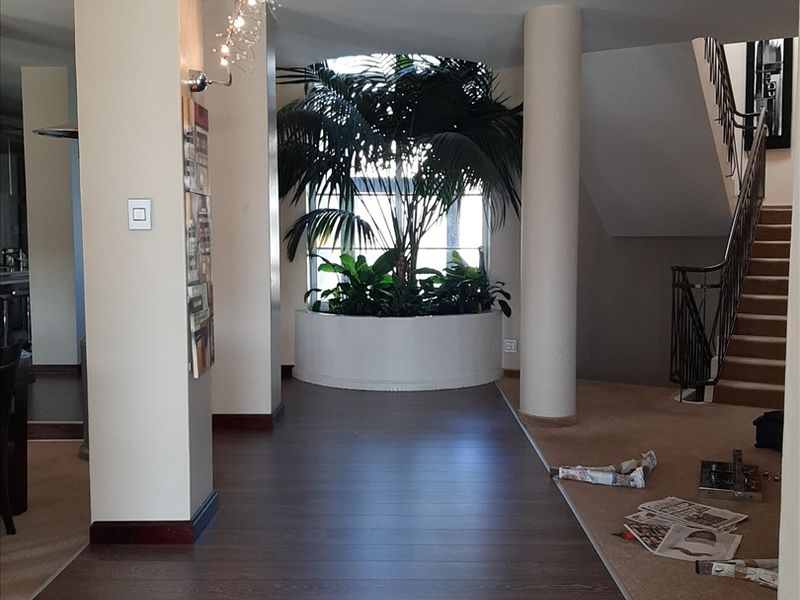 Spacious entrance hallway featuring a built-in circular planter, structural columns, and a staircase with a decorative wrought iron balustrade.