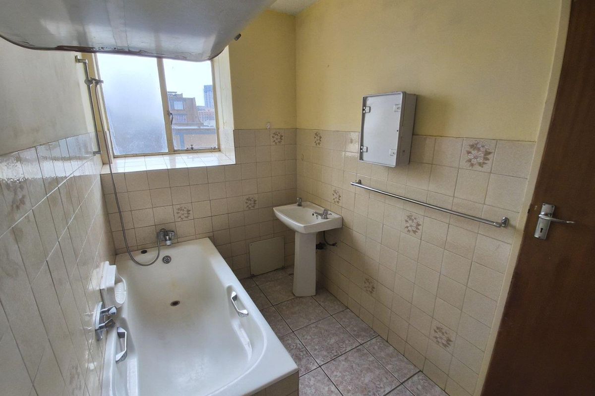 A dated bathroom featuring a standard bathtub, pedestal basin, and tiled walls. The space requires modernization to improve its overall condition and appeal.