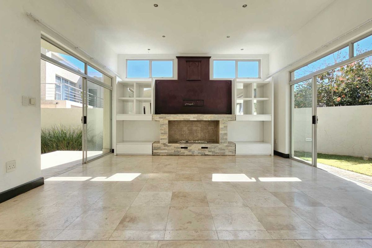 Spacious living area featuring a prominent built-in fireplace with stone detailing, custom shelving, and large sliding glass doors opening to the garden.