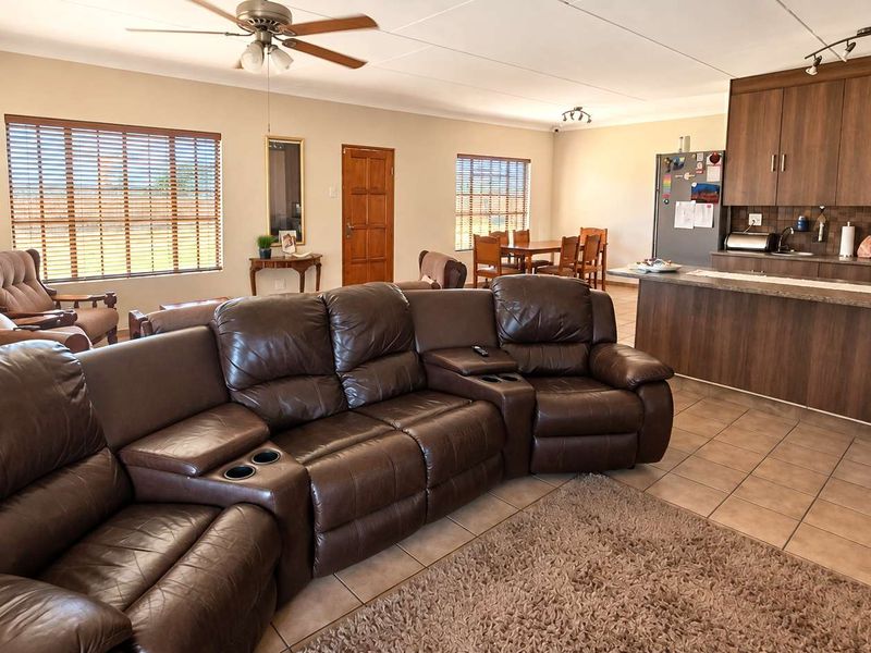 Spacious open-plan living area featuring tiled floors, a ceiling fan, and a functional kitchen with built-in cabinetry and a breakfast island.
