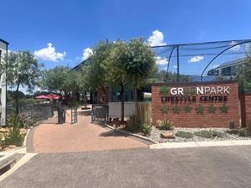 Entrance view of the Greenpark Lifestyle Centre featuring a brick signage wall, paved pathways, and well-maintained landscaped surroundings.