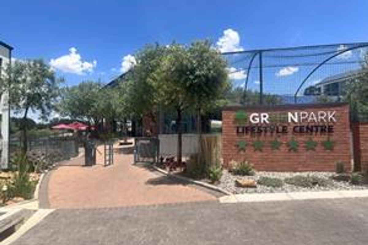 Entrance view of the Greenpark Lifestyle Centre featuring a brick signage wall, paved pathways, and well-maintained landscaped surroundings.