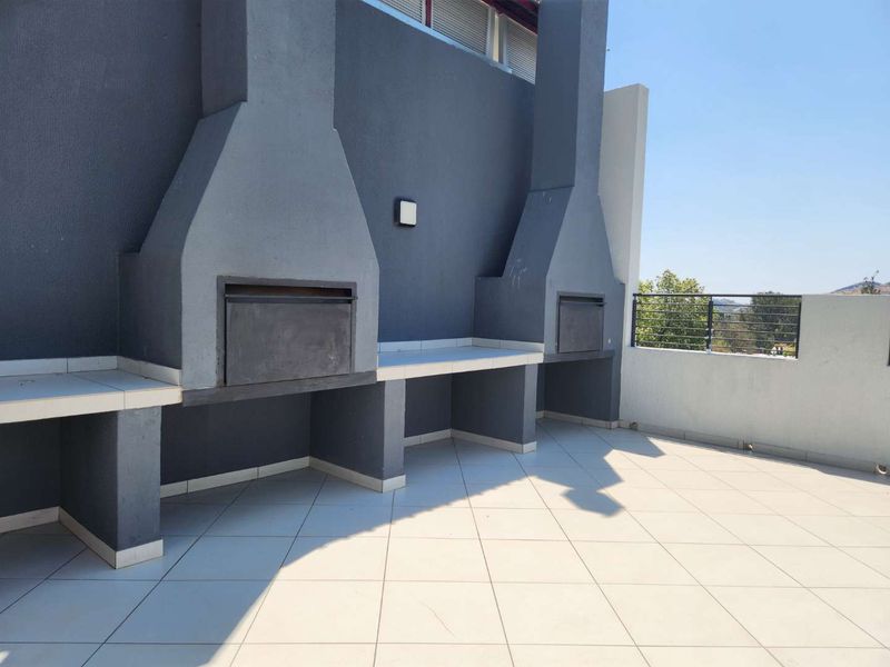 Spacious balcony featuring a dual built-in braai area with tiled surfaces, perfect for outdoor entertaining and enjoying the surrounding views.