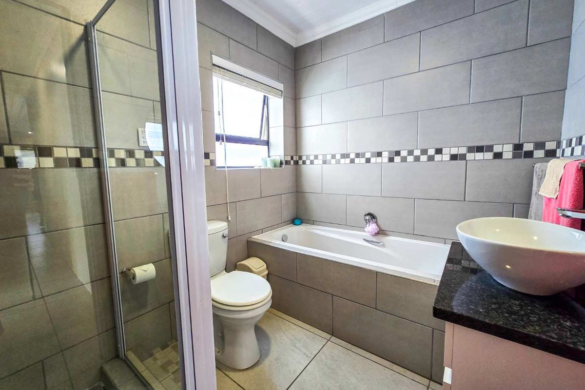 A modern bathroom featuring a tiled shower enclosure, a built-in bathtub, a toilet, and a vanity with a vessel sink.