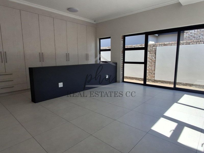 Spacious living area featuring extensive built-in cabinetry, large sliding glass doors, and modern tiled flooring with exposed brick accents.