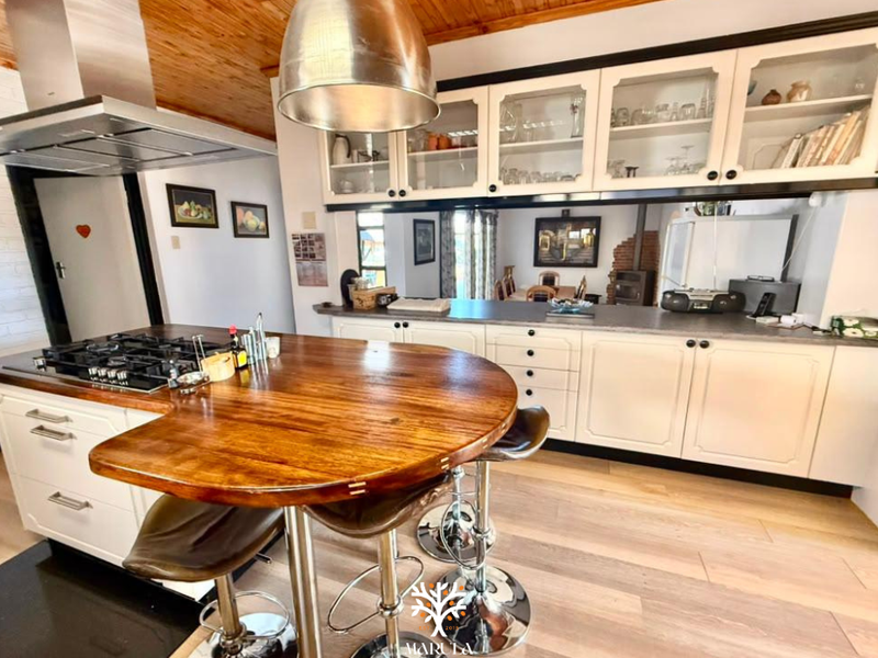 A well-appointed kitchen featuring a central island with a gas hob, timber ceiling, and ample built-in cabinetry with a breakfast bar.