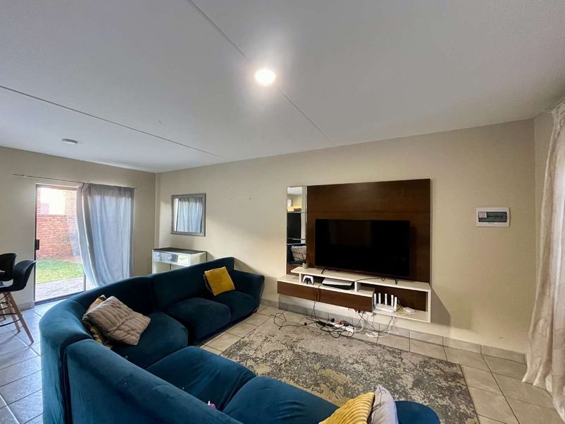 A living room featuring a built-in media console, tiled flooring, and a sliding glass door providing access to the outdoor area.