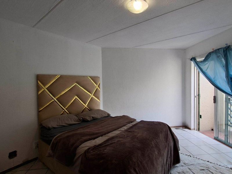 A bedroom featuring tiled flooring and a sliding glass door leading to an outdoor area, with visible ceiling damage and missing electrical outlet covers.
