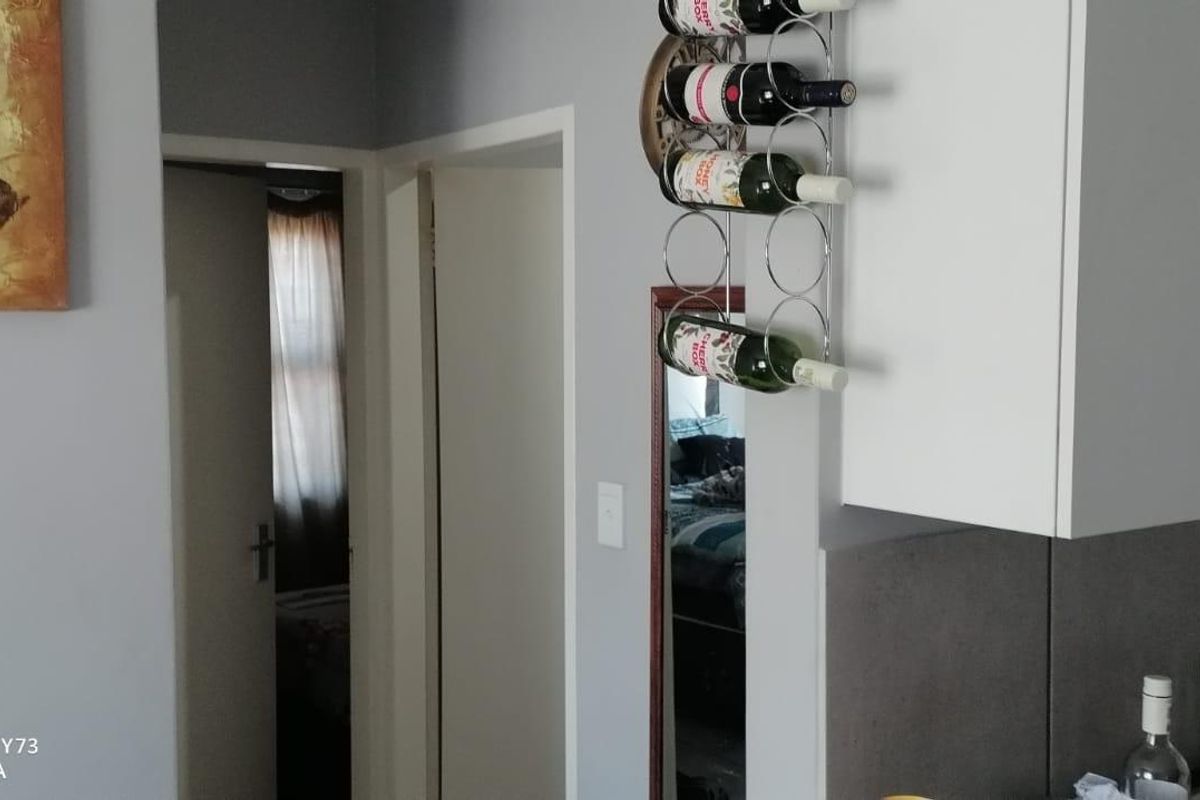 A view of a kitchen area featuring built-in cabinetry and a tiled backsplash, with a doorway leading to an adjacent room.
