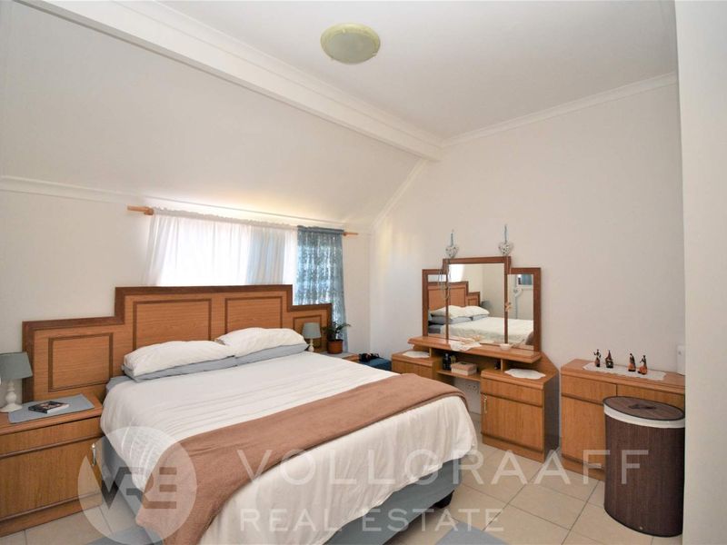 A bedroom featuring tiled flooring and a sloped ceiling, providing a functional space with neutral finishes.