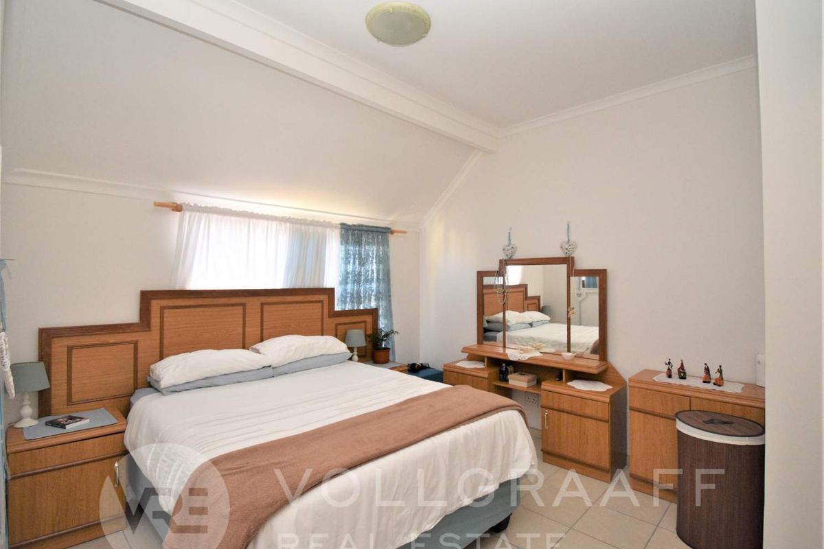 A bedroom featuring tiled flooring and a sloped ceiling, providing a functional space with neutral finishes.