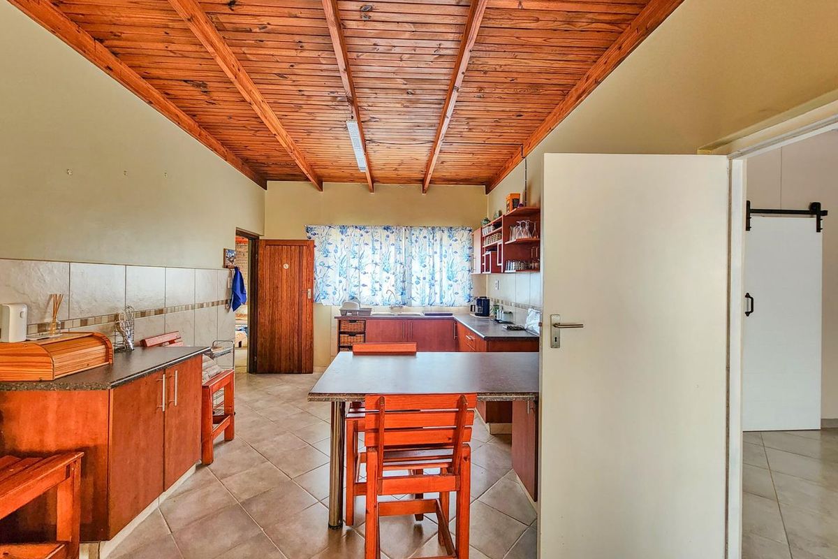 A functional kitchen featuring wooden cabinetry, tiled splashbacks, and a distinctive exposed timber beam ceiling, offering a traditional aesthetic with ample workspace.