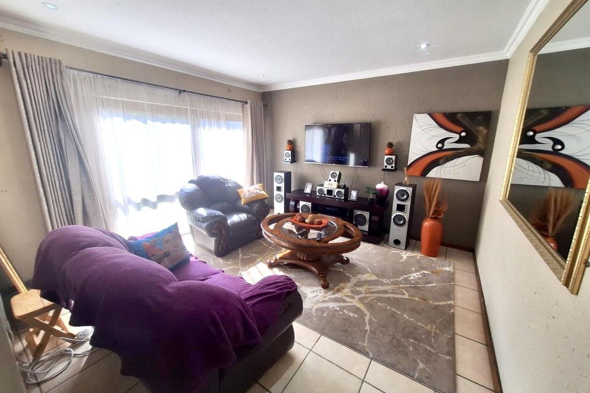 A comfortable living room featuring tiled flooring, recessed ceiling lighting, and large sliding glass doors that provide ample natural light.