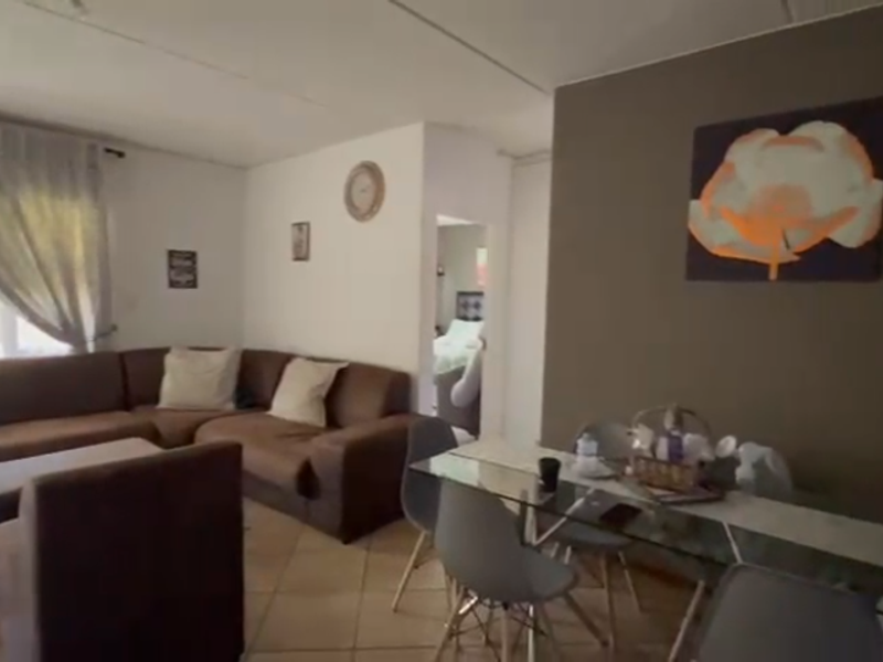 Open-plan living and dining area featuring tiled flooring and access to an outdoor space through a sliding door.