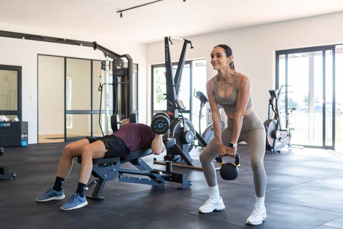 A modern, well-lit home gym featuring durable rubberized flooring and large sliding glass doors providing natural light and access to the exterior.