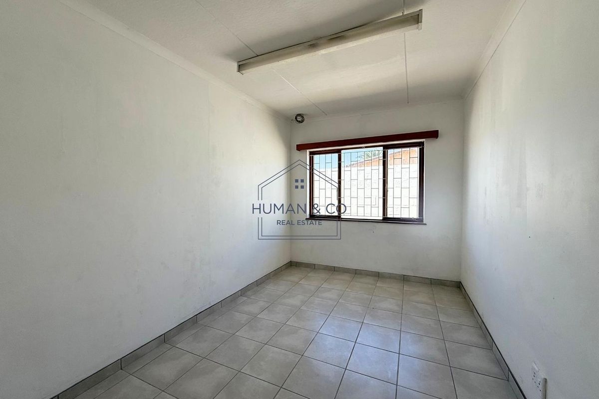 A vacant bedroom featuring tiled flooring, a security-barred window, and a basic fluorescent light fixture, offering a blank canvas for renovation.