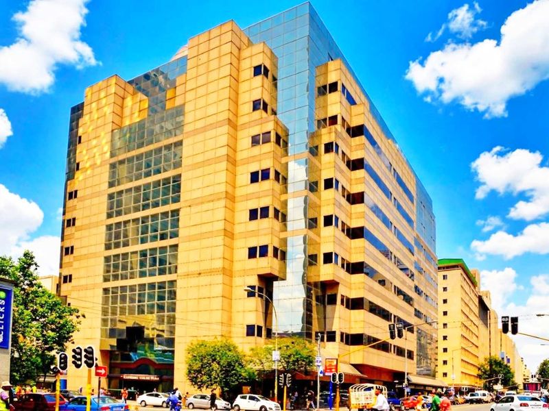 A multi-story commercial apartment building featuring a prominent glass and stone facade located in a busy urban street setting.