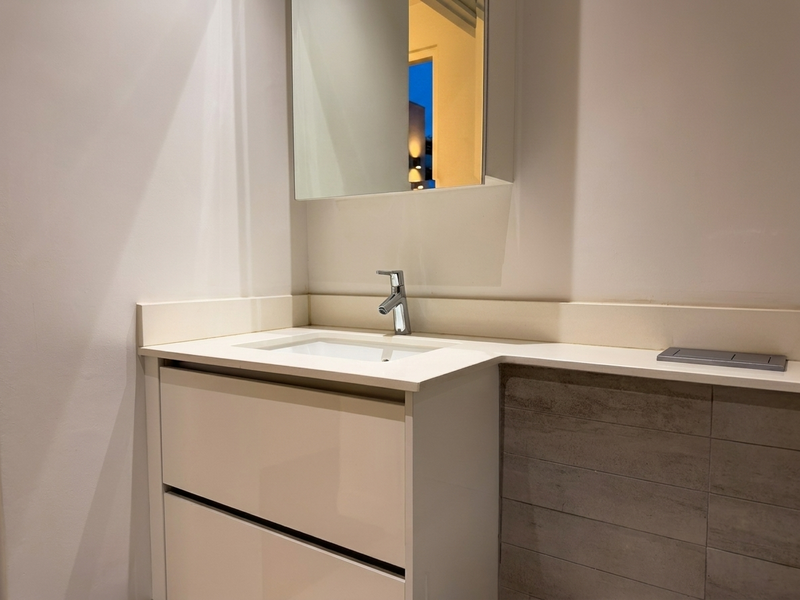 Modern bathroom vanity featuring a sleek integrated basin, chrome mixer tap, stone countertop, and a mirrored medicine cabinet with clean, contemporary finishes.