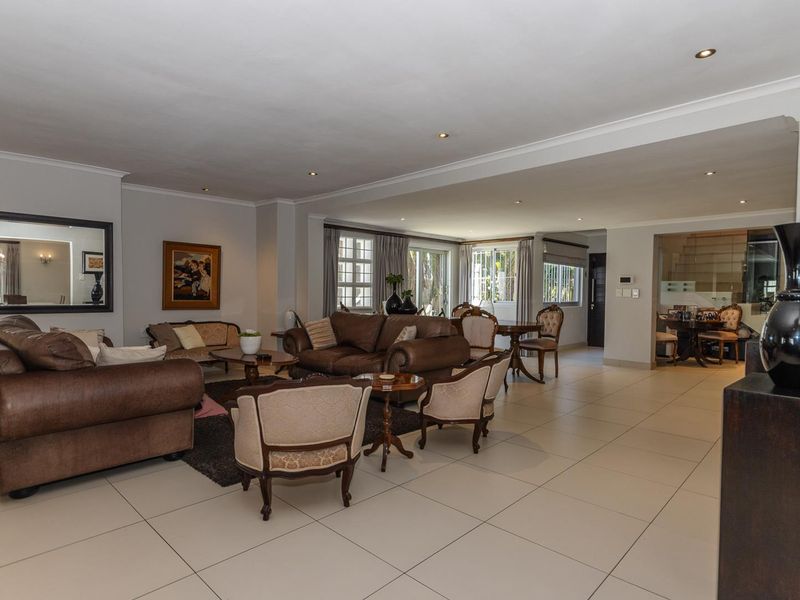 Spacious open-plan living area featuring neutral tiled flooring, recessed downlighting, and large sliding glass doors providing natural light and garden access.