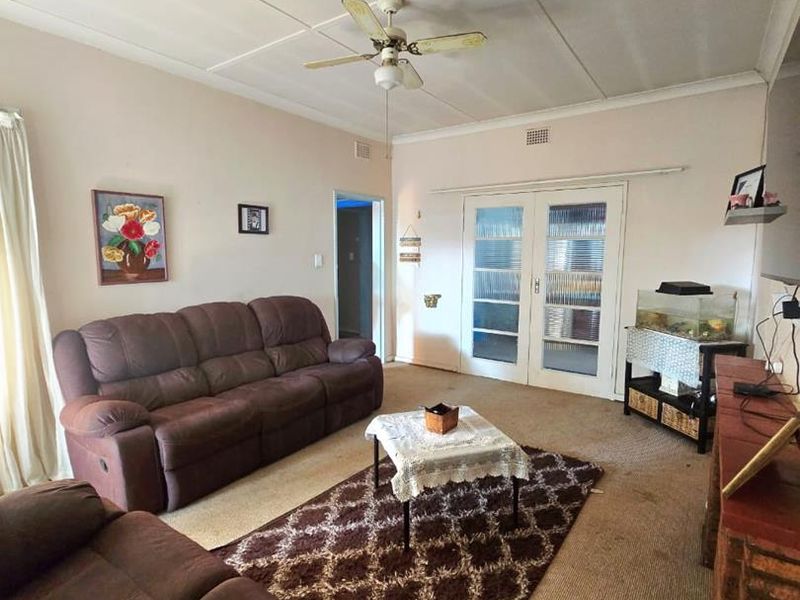 A living room featuring a ceiling fan, carpeted flooring, and glass-paneled french doors leading to an adjacent space.