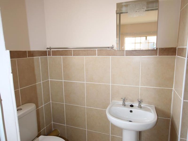 A compact guest bathroom featuring a pedestal basin, toilet, and neutral tiled finishes throughout.