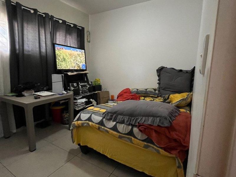 A compact bedroom featuring tiled flooring and a standard ceiling light fixture, providing a functional space for rest.