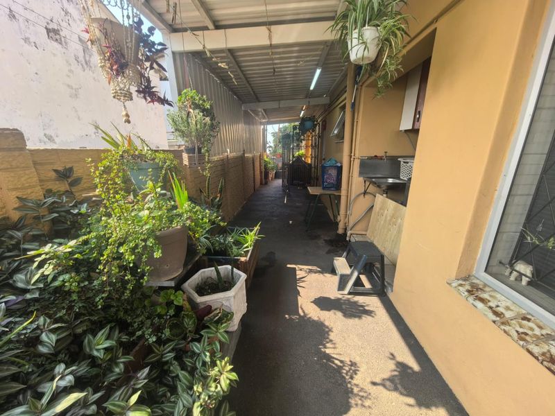 A covered side patio area featuring a built-in sink and direct access to the exterior, providing a functional utility space.