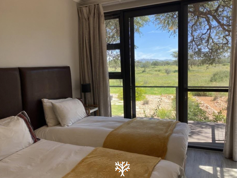 A bright bedroom featuring large glass sliding doors that open to a scenic outdoor view, complemented by modern laminate flooring and neutral finishes.