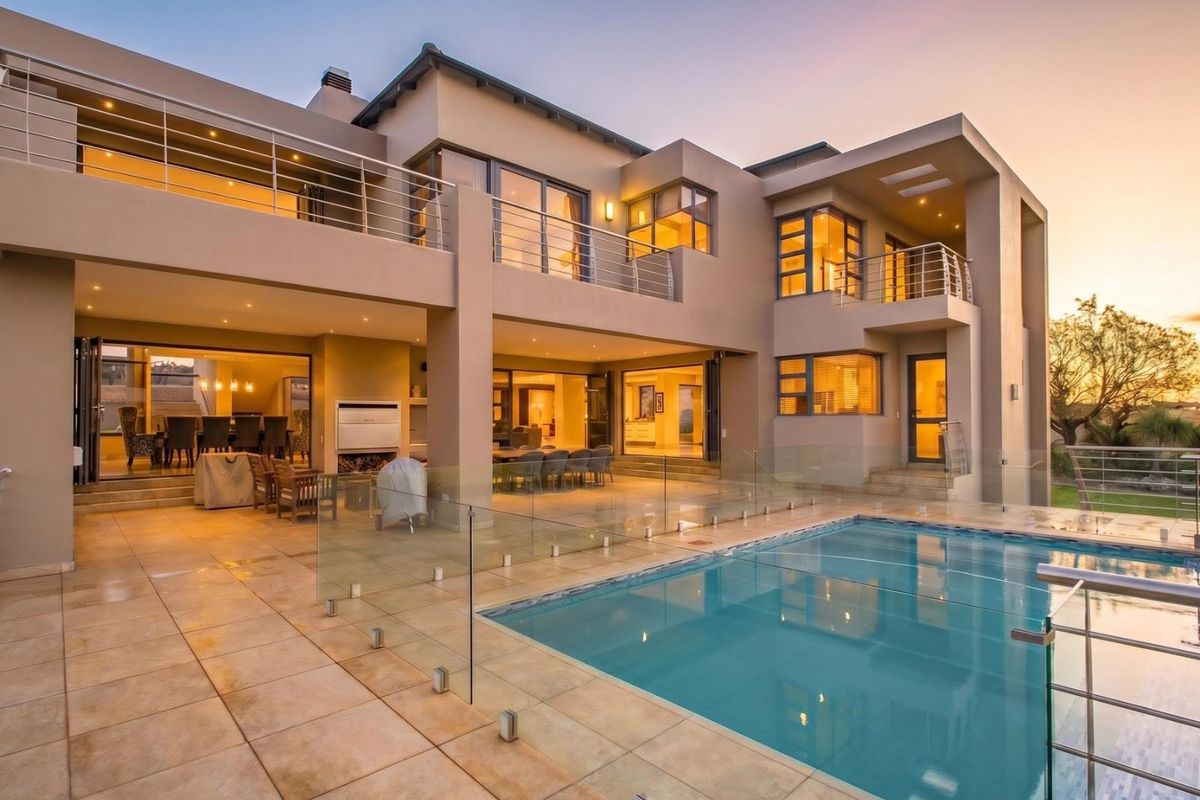 Modern double-story residence featuring a spacious covered patio, glass balustrades, and a pristine swimming pool, ideal for seamless indoor-outdoor entertaining.