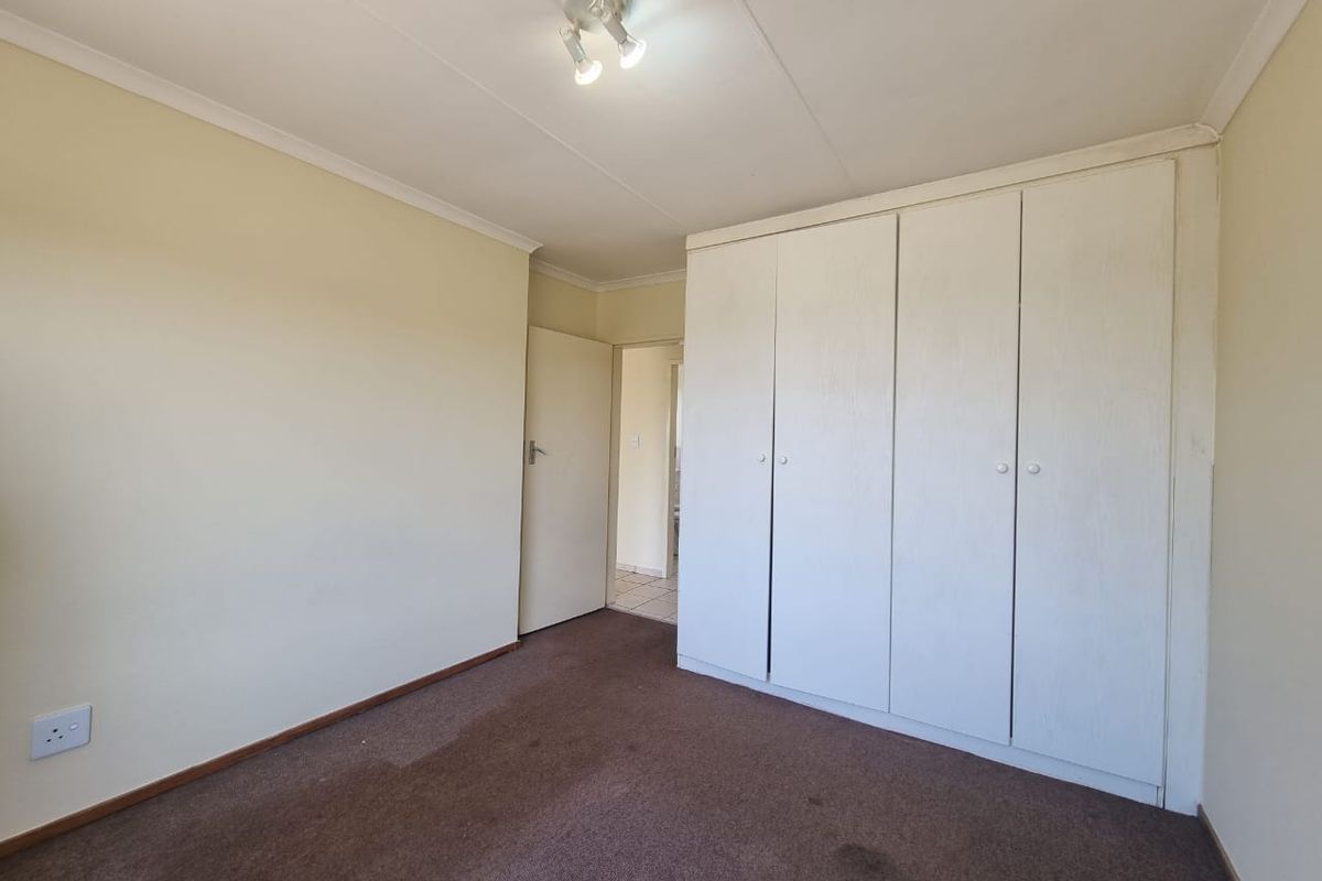 A vacant bedroom featuring built-in cupboards, carpeted flooring, and neutral wall finishes, offering a blank canvas for personalization.