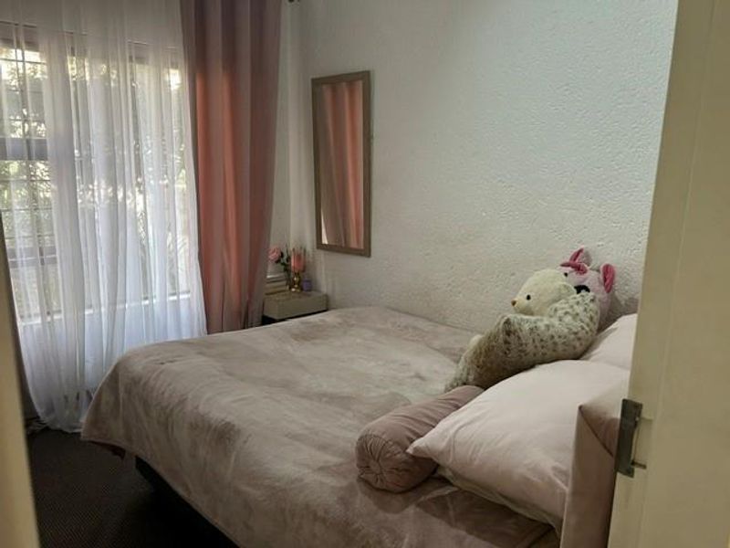 A cozy bedroom featuring a large window with curtains, providing natural light and a view of the exterior.