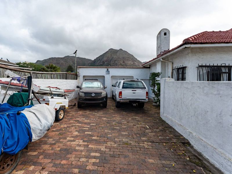 Front exterior view of the property featuring a brick driveway, double garage, and mountain backdrop.