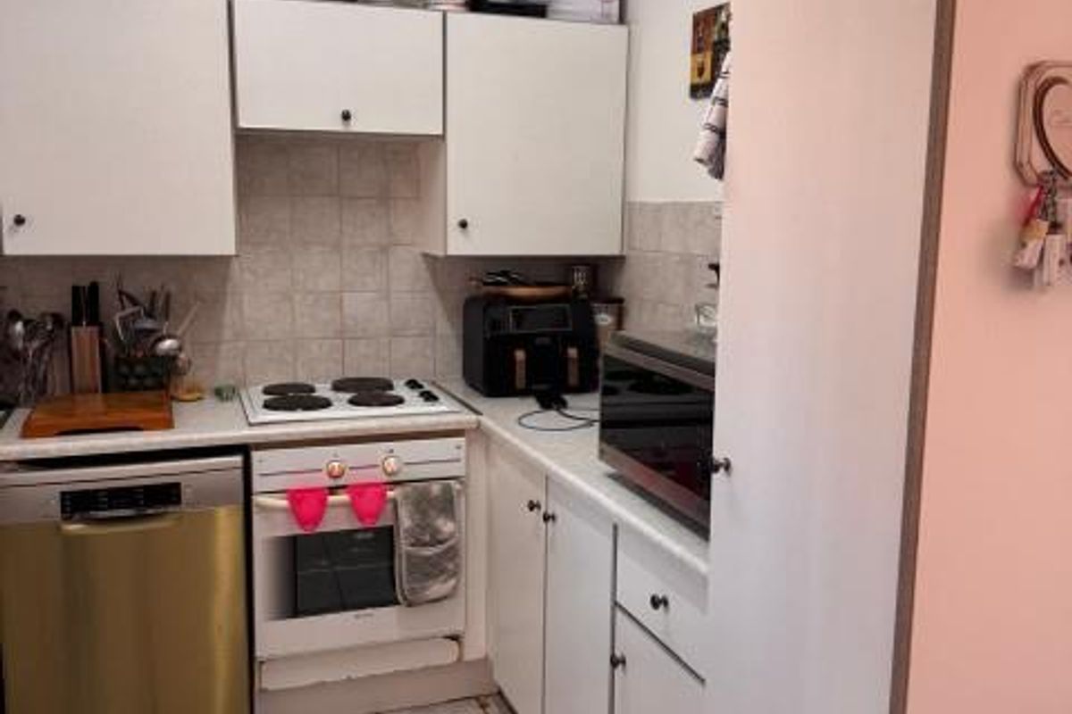 A functional kitchen featuring white cabinetry, a tiled backsplash, an electric hob, and built-in oven, providing a practical layout for daily meal preparation.