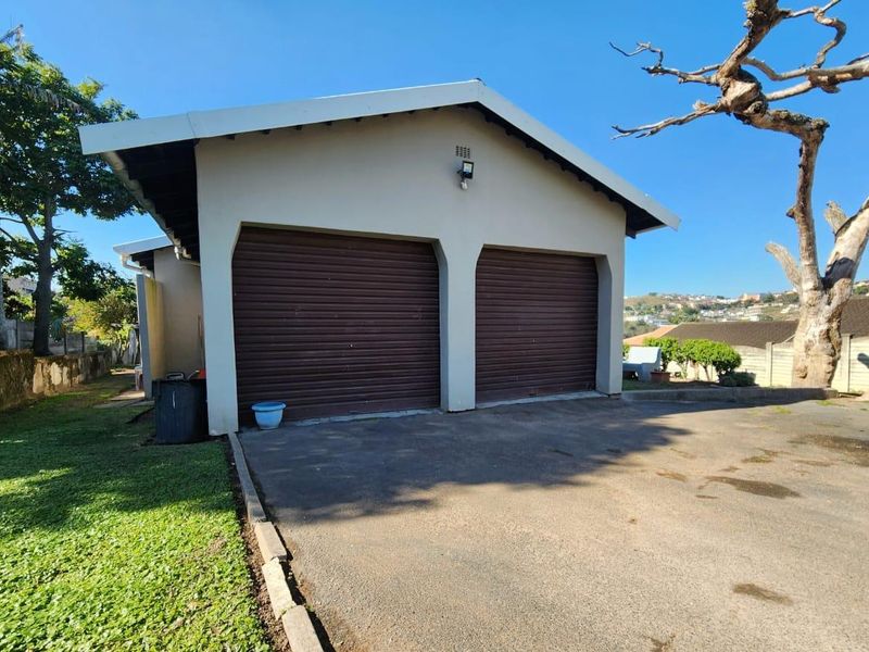A detached double garage featuring two roller doors and an asphalt driveway, set within a residential property.